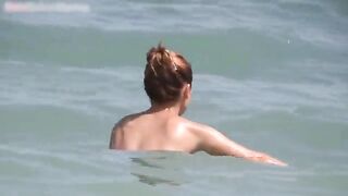 Redhead with big tits sunbathing topless and swimming in the sea without a bra